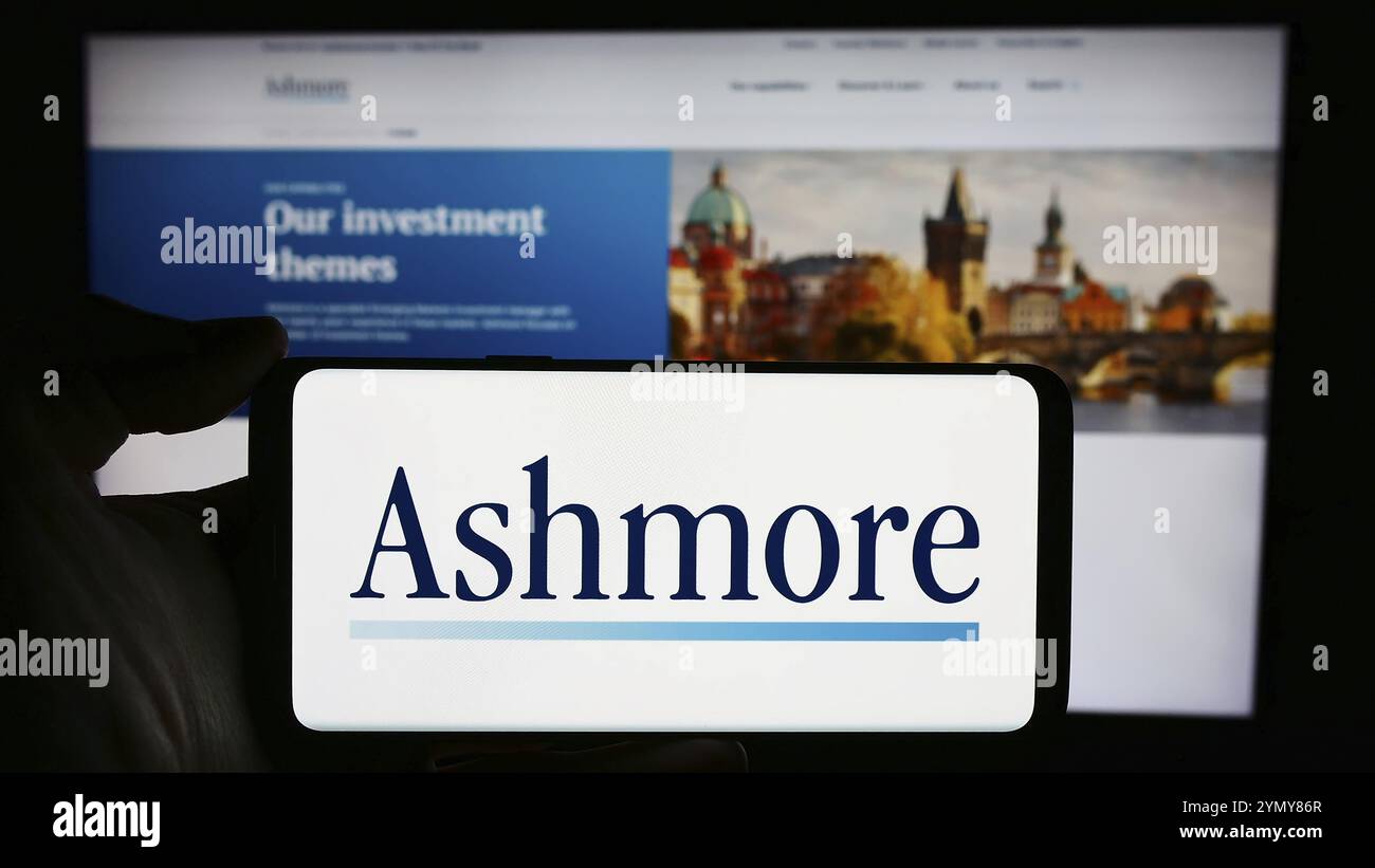 Stoccarda, Germania, 03-16-2024: Persona che detiene il cellulare con il logo della società britannica di gestione degli investimenti Ashmore Group plc davanti alla pagina web. FOC Foto Stock