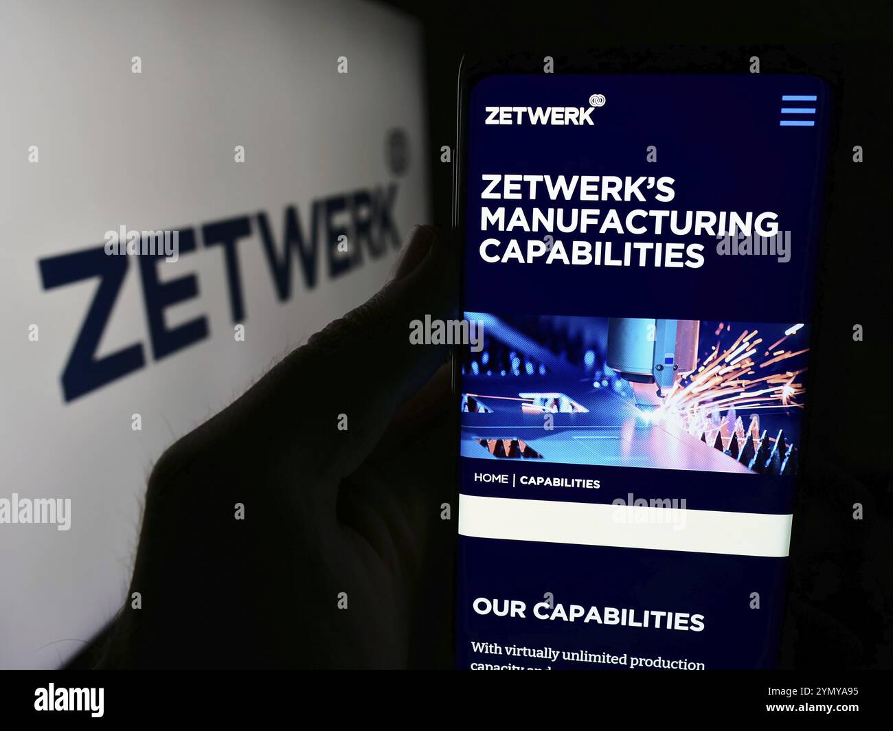 Stoccarda, Germania, 07-12-2024: Persona che detiene lo smartphone con pagina web della società indiana Zetwerk Manufacturing Businesses Pvt. Ltd. Con logo. Messa a fuoco o Foto Stock