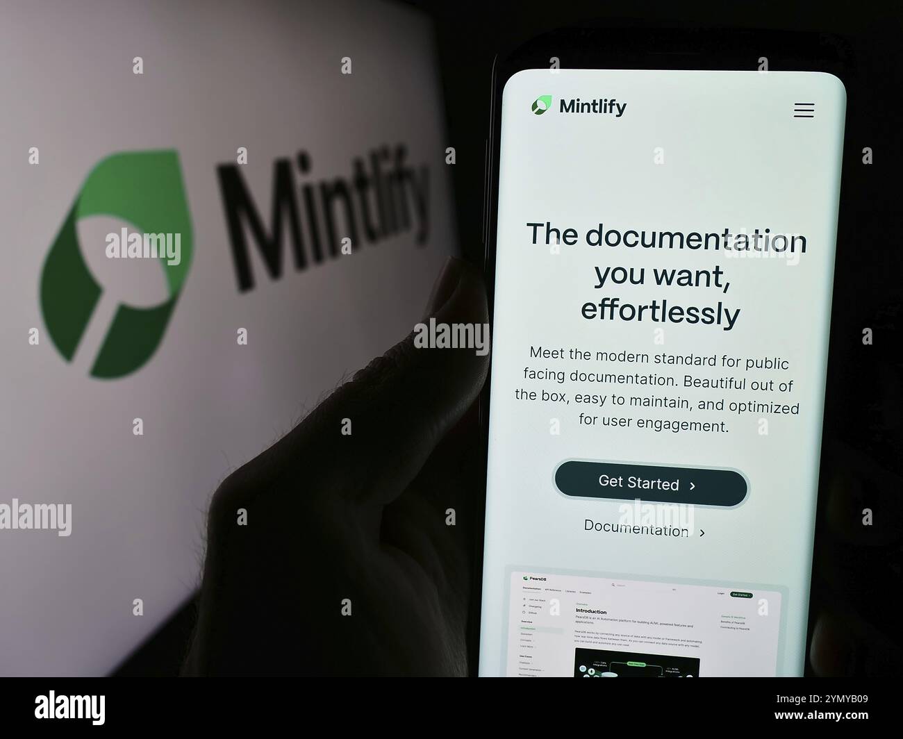 Stoccarda, Germania, 03-13-2024: Persona che tiene il cellulare con pagina web della società statunitense di documentazione Mintlify Inc. Davanti al logo. Concentratevi su ce Foto Stock