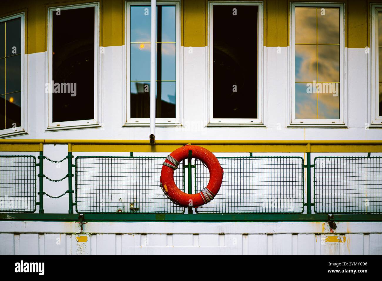 Lifebuoy rosso brillante montato su una ferrovia colorata con sfondo industriale Foto Stock