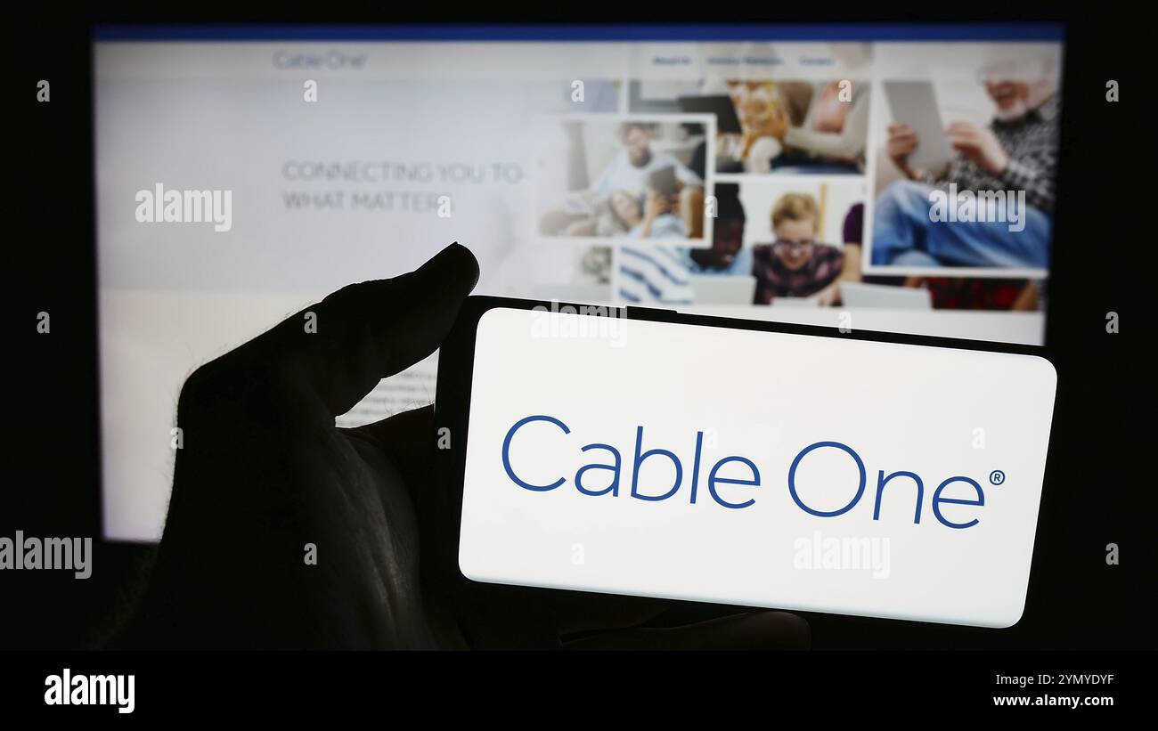 Stoccarda, Germania, 07-06-2024: Persona che detiene uno smartphone con il logo della società di telecomunicazioni statunitense Cable One Inc. Davanti al sito web. Concentrati sul phon Foto Stock