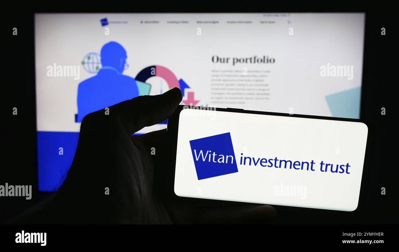 Stoccarda, Germania, 05-31-2024: Persona che detiene un telefono cellulare con il logo della società britannica Witan Investment Trust plc di fronte alla pagina web aziendale. FOC Foto Stock