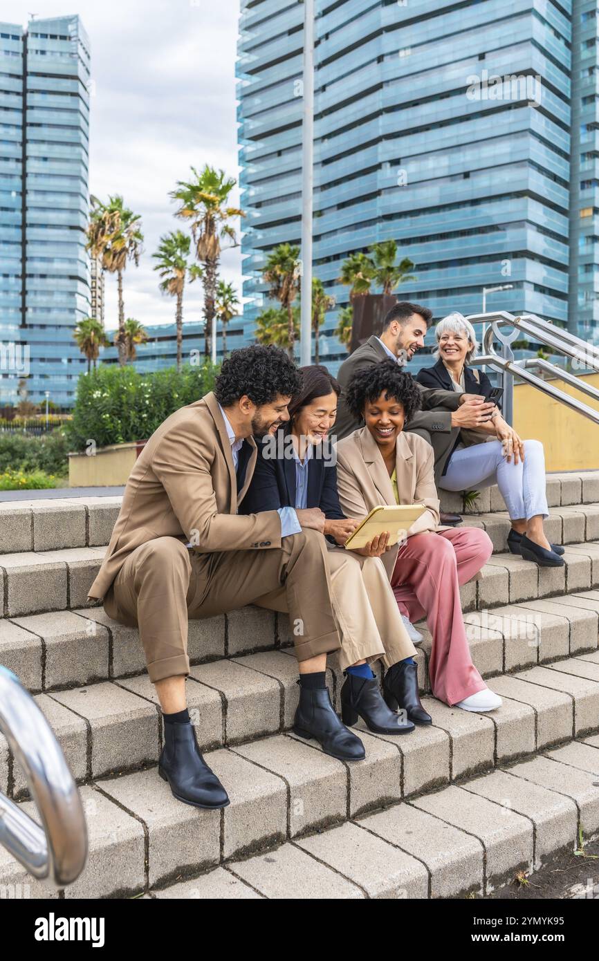 Foto verticale di un gruppo eterogeneo di persone che lavorano con un tablet digitale in città Foto Stock