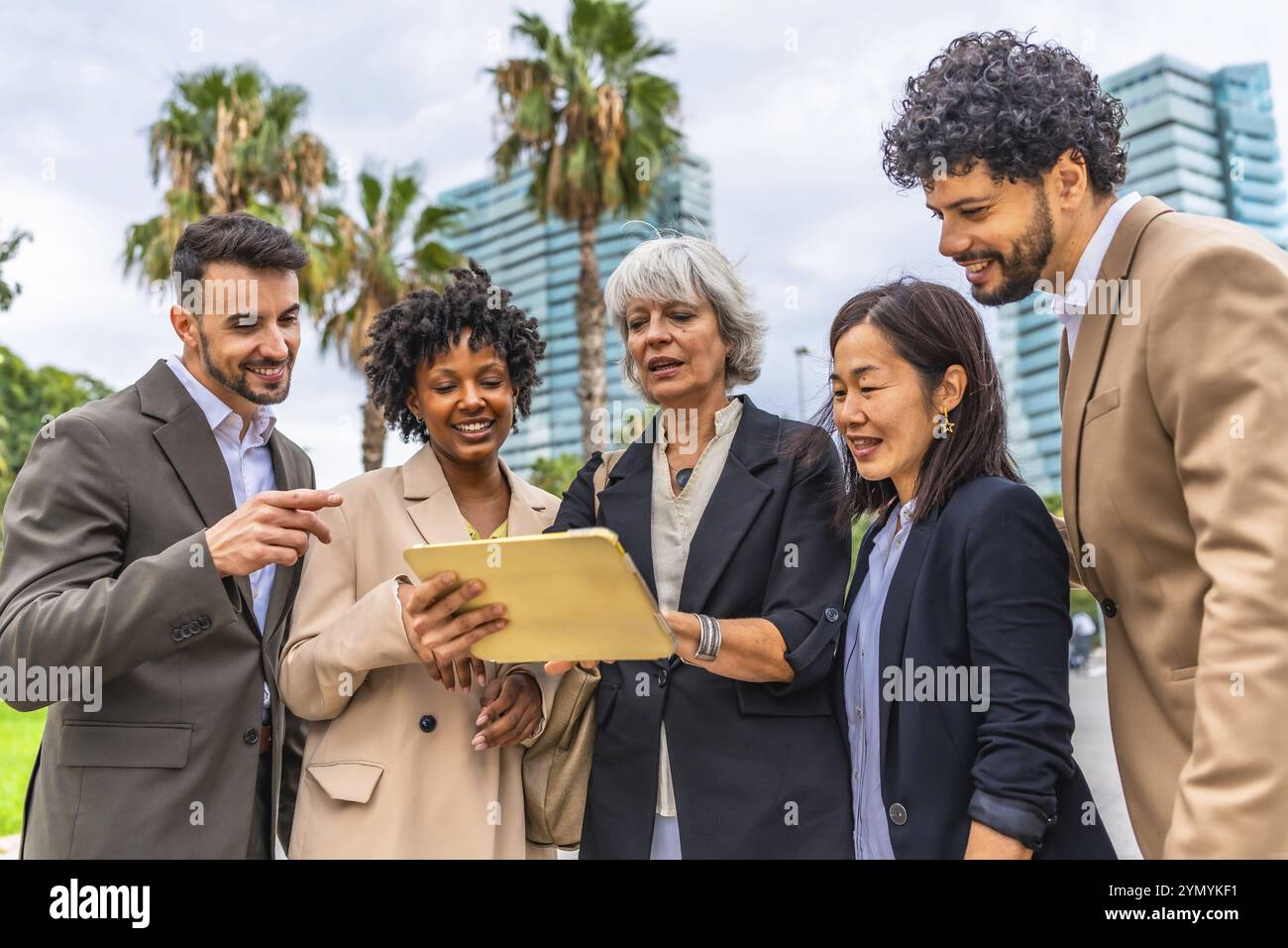Donna d'affari matura che utilizza un tablet digitale mentre parla con colleghi aziendali multietnici durante una riunione all'aperto Foto Stock