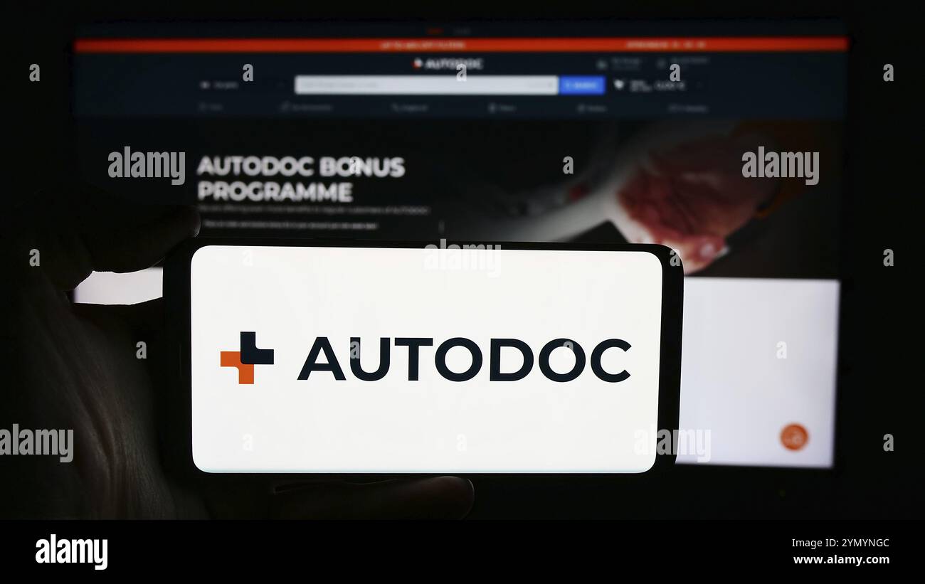 Stoccarda, Germania, 05-24-2024: Persona che detiene il cellulare con il logo della società tedesca di e-commerce AutoDoc se di fronte alla pagina web aziendale. FOC Foto Stock