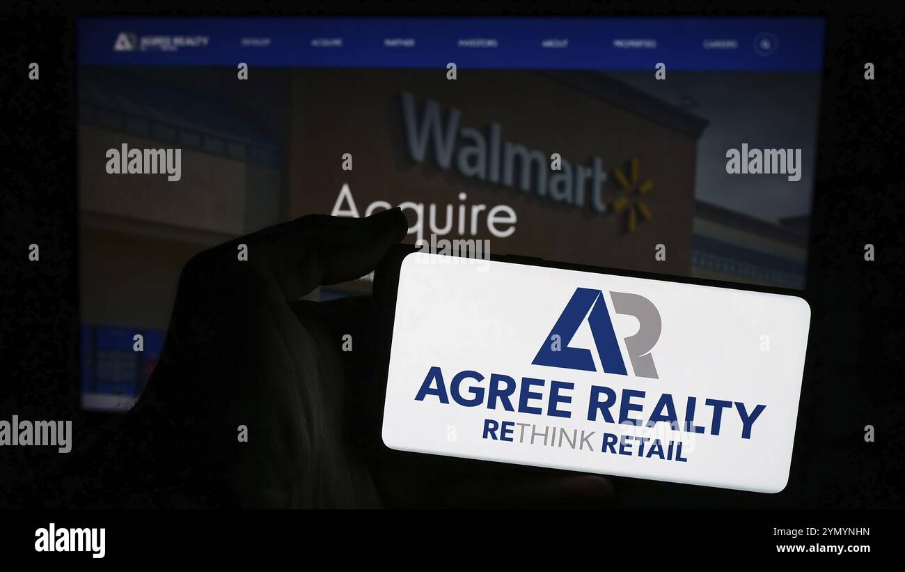 Stoccarda, Germania, 04-28-2024: Persona che possiede uno smartphone con il logo della società immobiliare statunitense Accetto Realty Corporation davanti al sito web. Concentrati su p Foto Stock