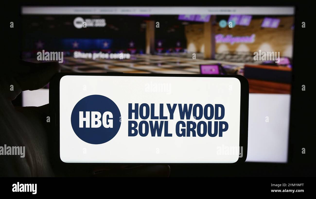 Stoccarda, Germania, 03-20-2024: Persona che tiene il cellulare con il logo della società britannica di bowling Hollywood Bowl Group plc di fronte alla pagina web aziendale. F Foto Stock