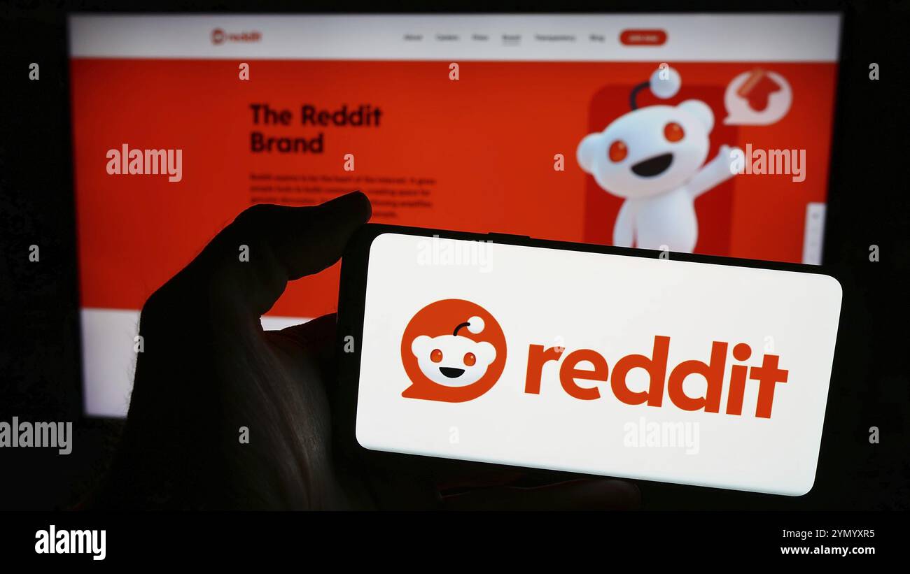 Stuttgart, Germania, 03-15-2024: Persona con smartphone con logo della società statunitense di social media Reddit Inc. Davanti al sito web. Mettere a fuoco il display del telefono Foto Stock