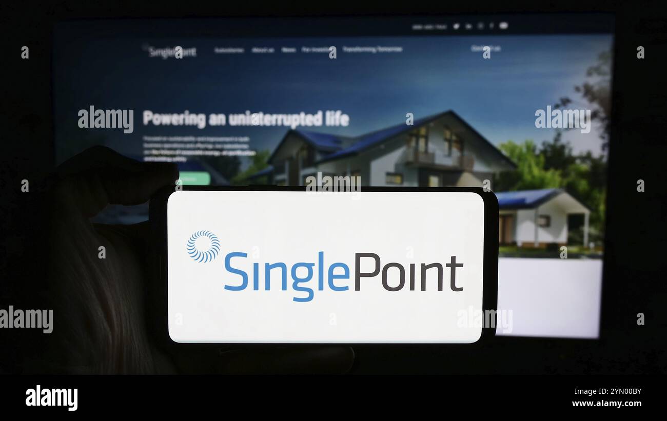 Stoccarda, Germania, 05-06-2024: Persona che detiene un cellulare con il logo della società statunitense di energia rinnovabile SinglePoint Inc. Di fronte alla pagina web aziendale. Concentrati Foto Stock