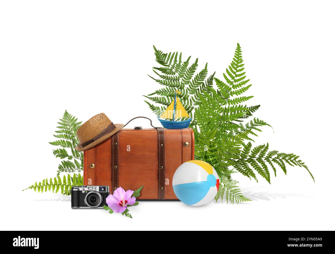 Valigia da viaggio marrone, cappello, macchina fotografica, barca a vela giocattolo, palla da spiaggia, foglie tropicali e fiori su sfondo bianco Foto Stock