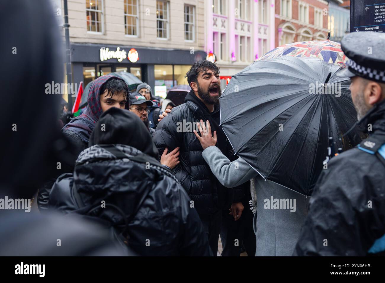 Leeds, Regno Unito. 23 NOVEMBRE 2024. Man grida al sostenitore pro israeliano alla marcia settimanale Palestina del PSC di Leeds, intrapresa nelle avverse condizioni meteorologiche causate da Storm Bert, così come due gruppi di protesta rivali che si riuniscono fuori Leeds Corn Exchange e portano ad un cambio di rotta. Credito Milo Chandler/Alamy Live News Foto Stock