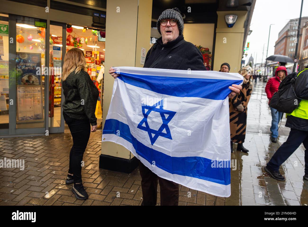 Leeds, Regno Unito. 23 NOVEMBRE 2024. La controprotesta pro Israel detiene la bandiera israeliana alla marcia settimanale Palestina del PSC di Leeds, intrapresa nelle avverse condizioni meteorologiche causate da Storm Bert, così come due gruppi di protesta rivali che si riuniscono fuori Leeds Corn Exchange e portano ad un cambio di rotta. Credito Milo Chandler/Alamy Live News Foto Stock