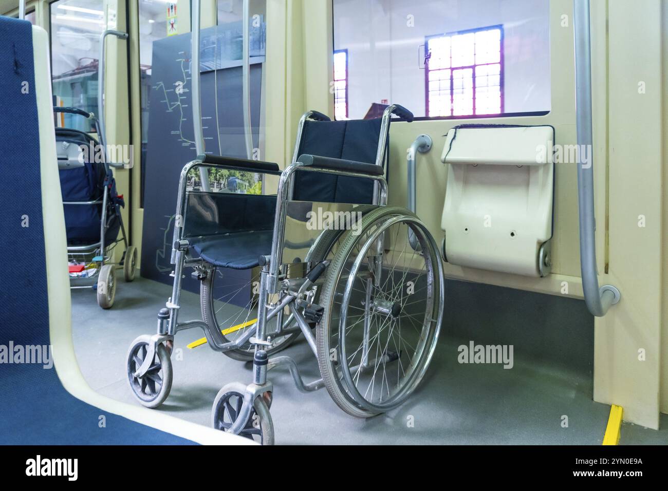 Una sedia a rotelle è seduta in una stazione ferroviaria. La sedia a rotelle è nera e argento Foto Stock