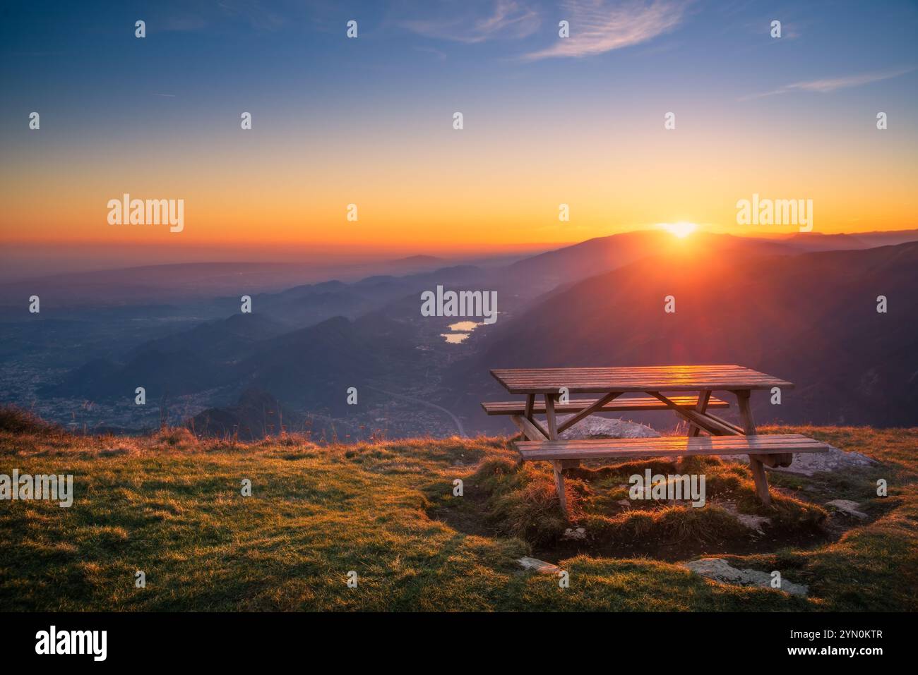 Uno splendido tramonto proietta colori vivaci sul Monte Pizzoc nella zona di Cansiglio in Veneto mentre il sole si abbassa dietro le montagne Foto Stock