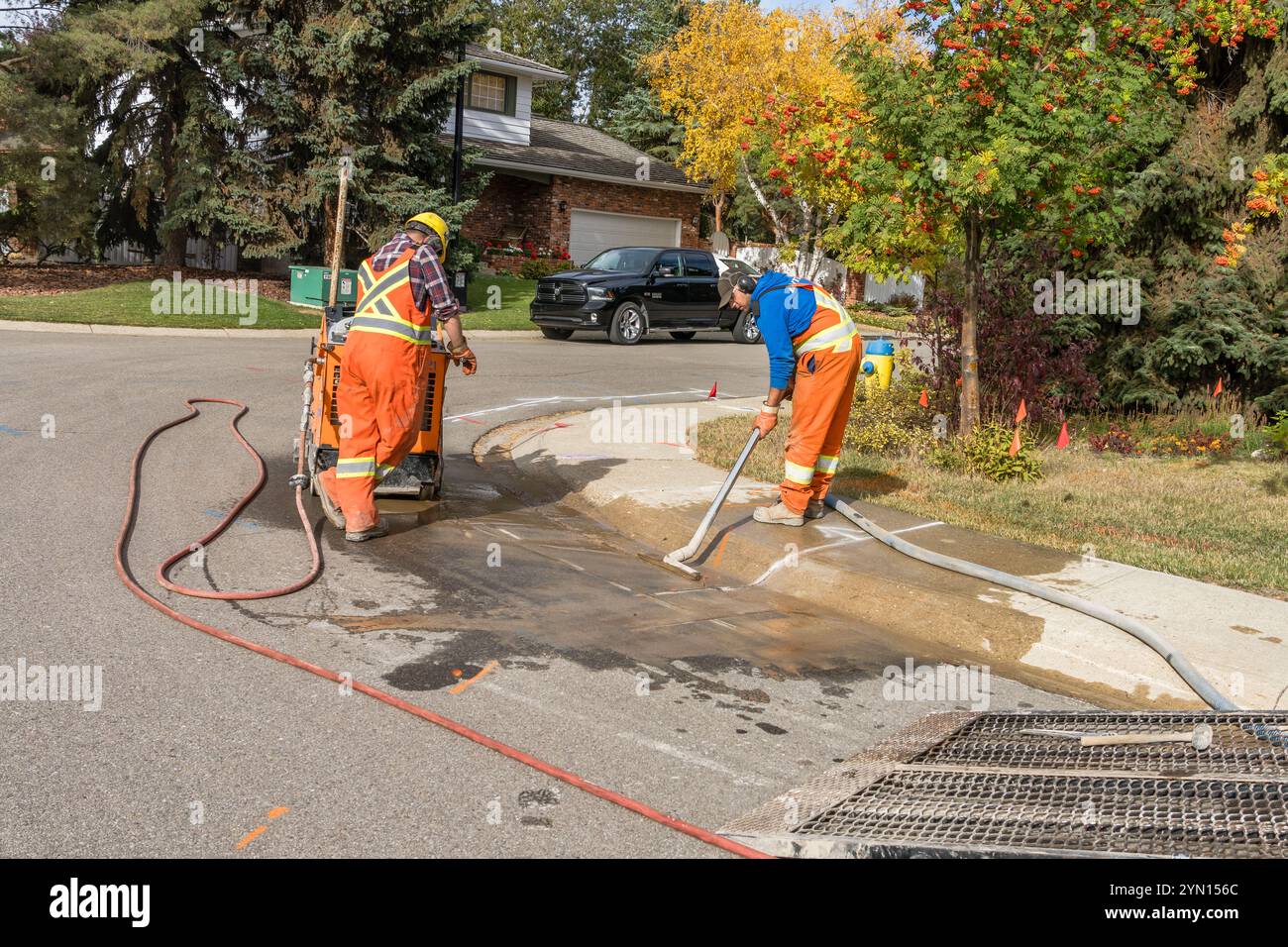 Edmonton, Canada, 7 ottobre 2024: Due operai eseguono lavori di preparazione per la riparazione del marciapiede con asfalto e marciapiede tagliati per la rimozione Foto Stock