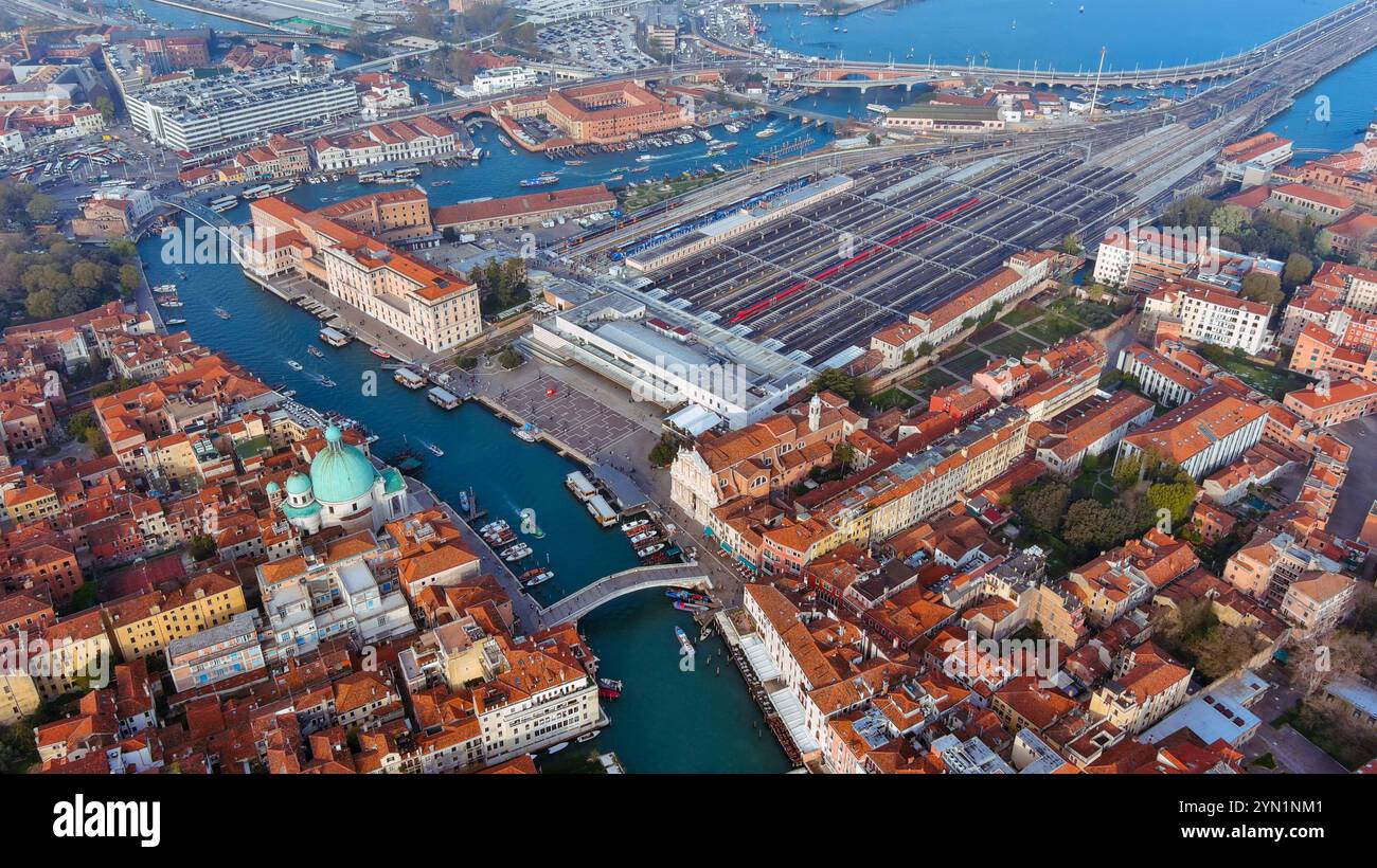 Suggestiva vista aerea della stazione ferroviaria di Venezia e del Canal grande, animata da barche e circondata dall'architettura senza tempo della città Foto Stock