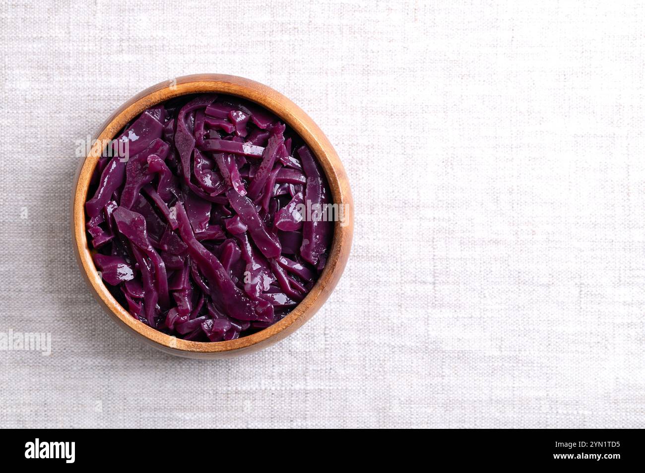 Cavolo rosso brasato in una ciotola di legno, con spazio vuoto per il testo. Contorno tedesco tradizionale di colore viola intenso, fatto di cavolo a fette. Foto Stock