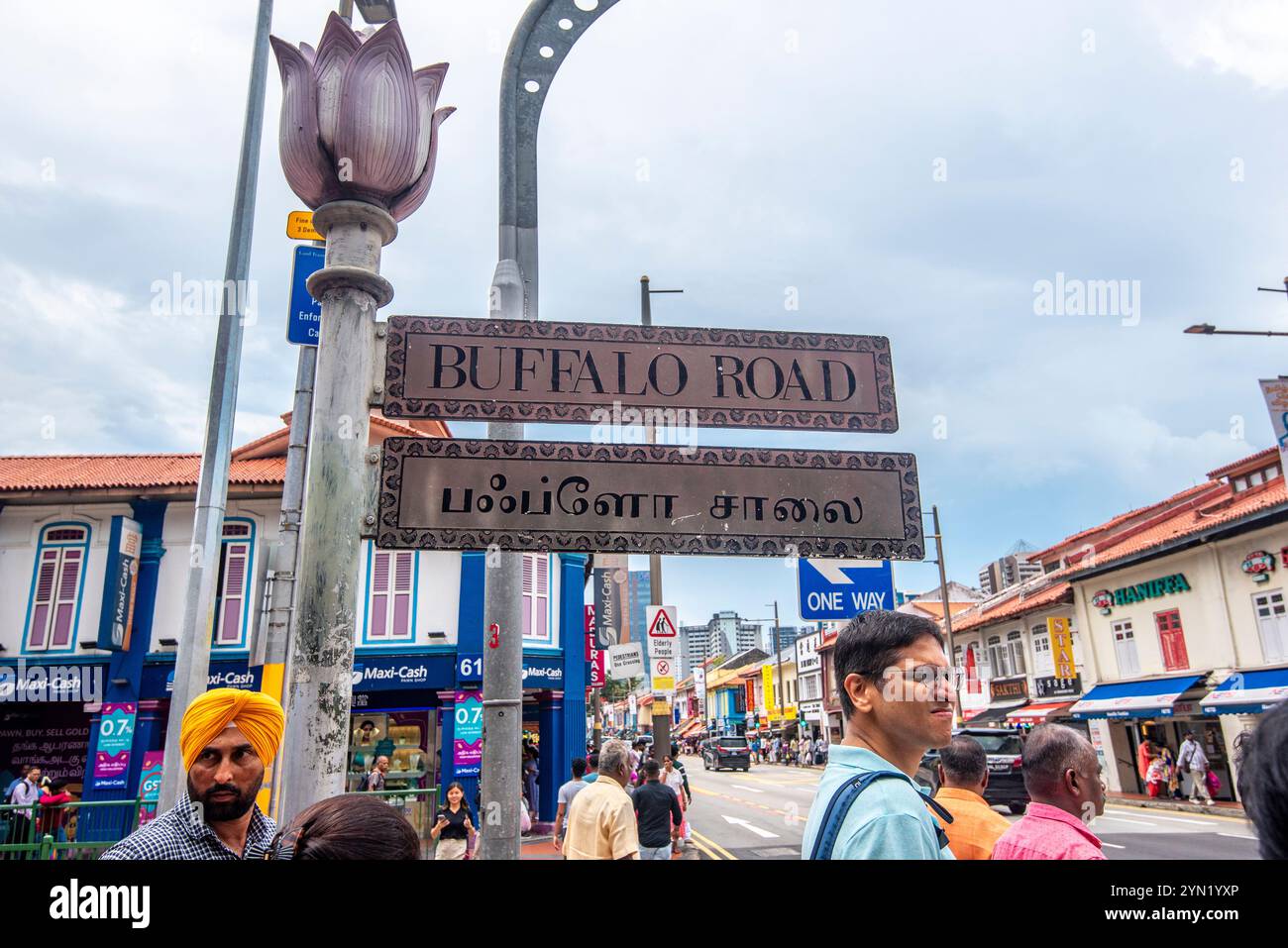 Persone in piedi accanto a un cartello bilingue in lingua doppia su Buffalo Road a Little India, Singapore Foto Stock