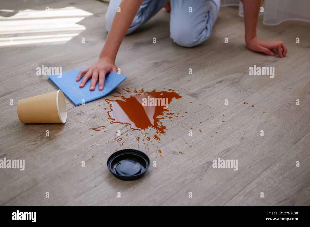 La tazza di carta di caffè è caduta su laminato, caffè versato sul pavimento. Foto Stock