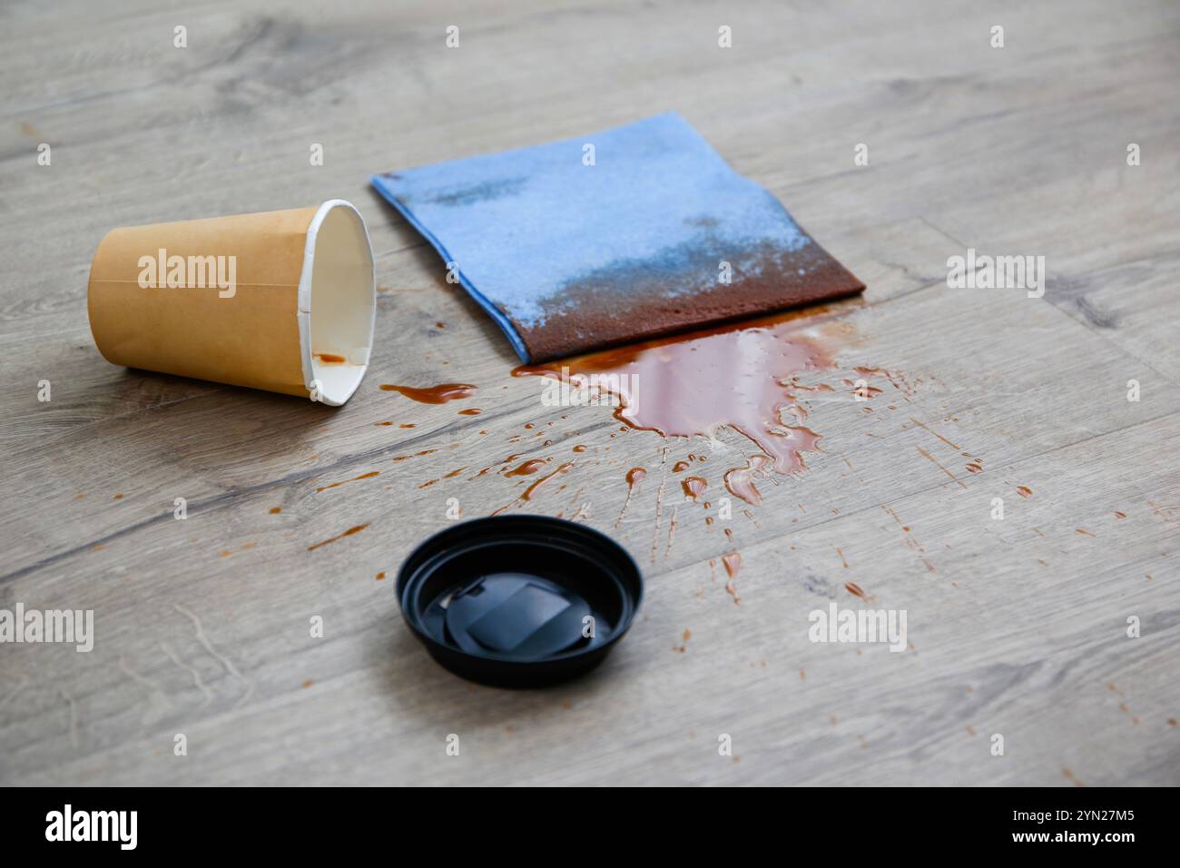 La tazza di carta di caffè è caduta su laminato, caffè versato sul pavimento. Foto Stock