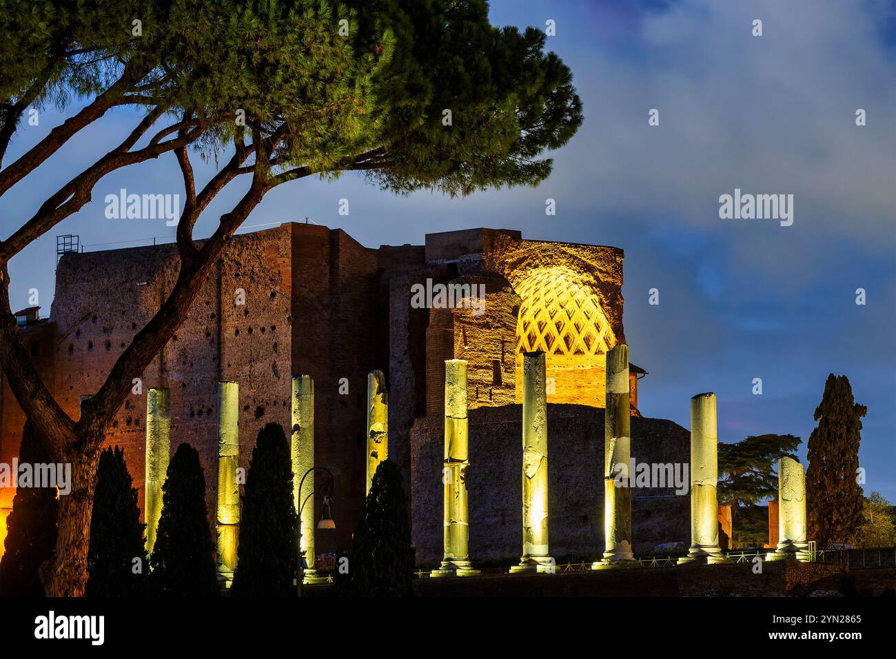 Una veduta di antiche colonne che costeggiano la via Sacra a Roma, Italia, con le rovine della Basilica di Massenzio visibili sullo sfondo. Foto Stock
