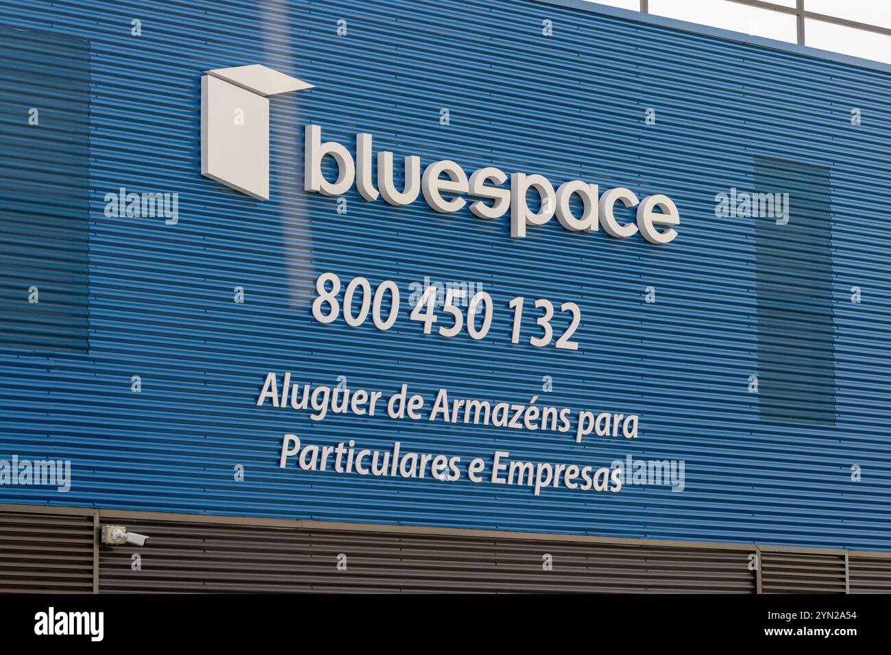 Logo Bluespace e informazioni di contatto esposte su una facciata blu di un edificio in metallo, che offre il noleggio di articoli per privati e aziende Foto Stock