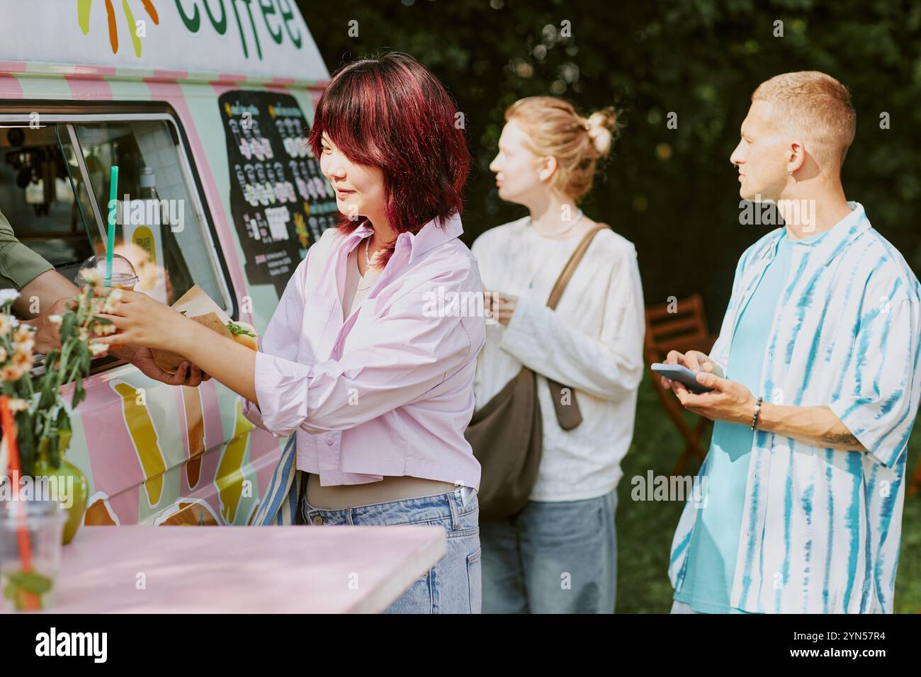 Clienti multirazziali in piedi accanto al food truck leggendo il menu e prendendo ordini Foto Stock