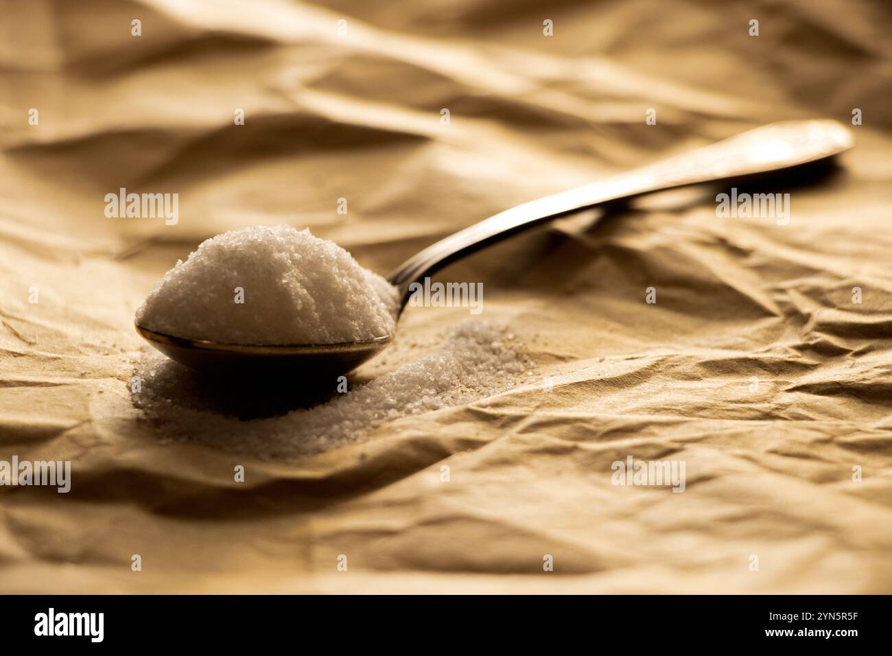 Cucchiaio pieno di sale da tavola su carta marrone da primo piano, sale Foto Stock