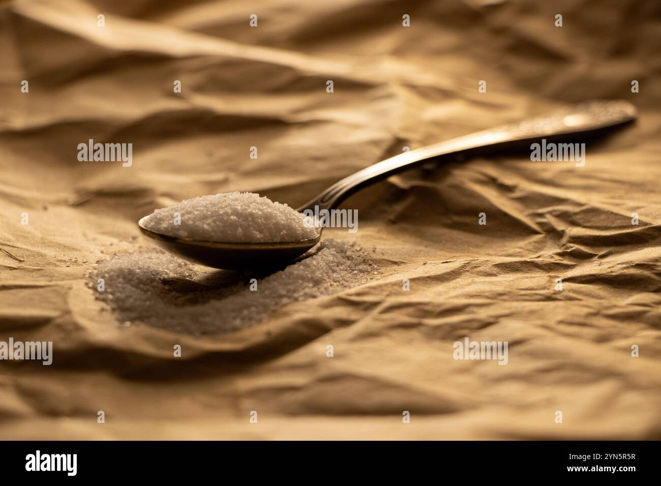 Cucchiaio pieno di sale da tavola su carta marrone da primo piano, sale Foto Stock