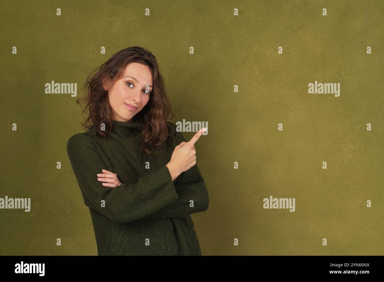 Stili di vita, business e concetto di marketing. Una donna sorridente in un comodo maglione verde la punta a sinistra su uno sfondo verde Foto Stock