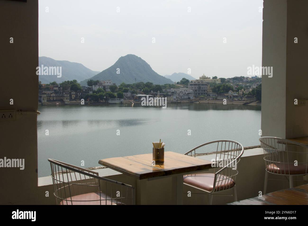 Tavolo e sedie del ristorante con vista sul lago di Pushkar e sulle montagne dalla terrazza nel Rajasthan, India Foto Stock