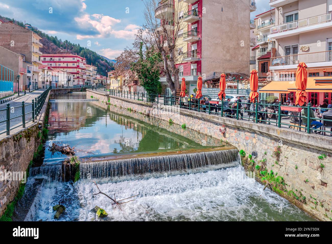 Fiume Sakoulevas con edifici residenziali e caffè sul marciapiede lungo la costa. A Florina, Macedonia, Grecia. Foto Stock