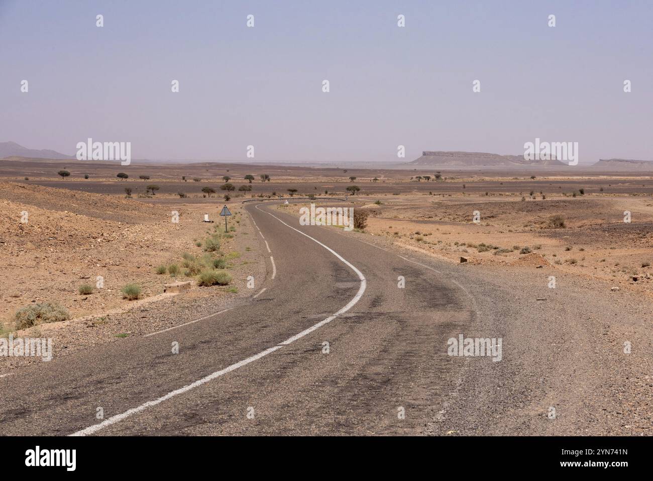 Una strada che conduce attraverso il deserto vicino a Merzouga, il famoso monte a ferro di cavallo gara Medouar sullo sfondo, Marocco, Africa Foto Stock