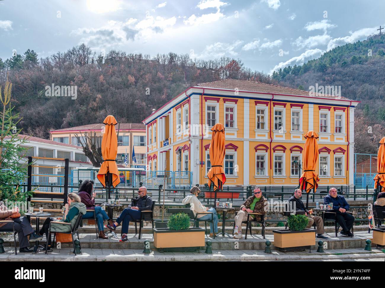 Caffè sul marciapiede sulla costa del fiume Sakoulevas con case neoclassiche sullo sfondo. A Florina, Macedonia, Grecia. Foto Stock