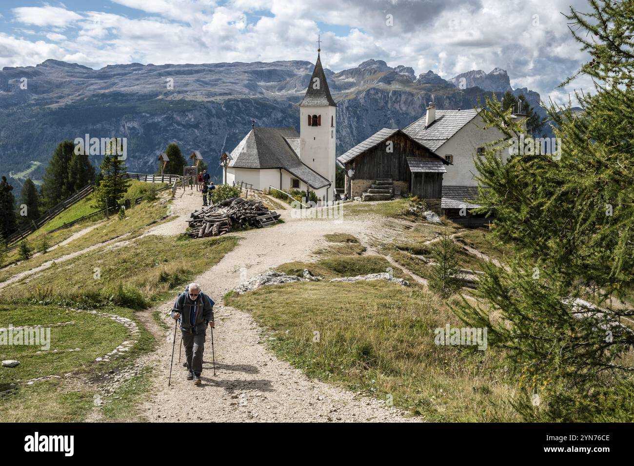 Un anziano escursionista nelle Alpi dolomitiche, la chiesa Heilig Kreuz sullo sfondo, il Tirolo meridionale in Italia Foto Stock