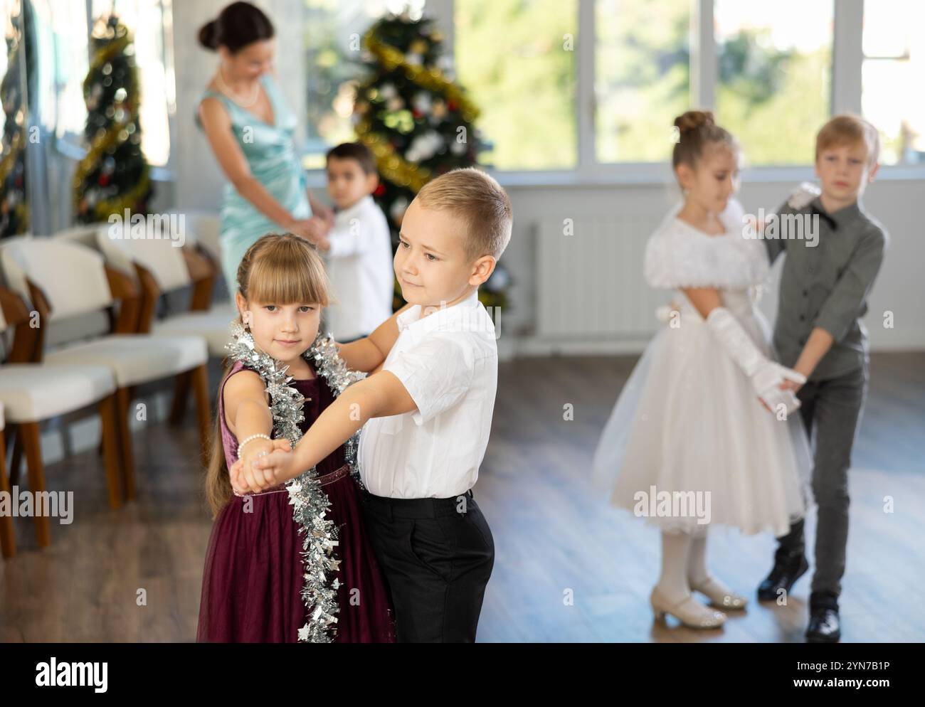 Bambini preadolescenti in abiti eleganti che praticano la danza di coppia nello studio natalizio Foto Stock