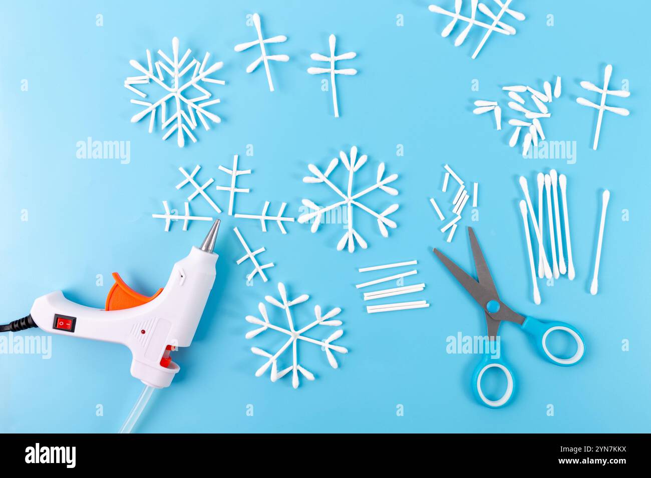 Istruzioni dettagliate su come realizzare il fiocco di neve con bastoncini di cotone, processo creativo, attività di preparazione natalizia per i bambini, vista dall'alto Foto Stock