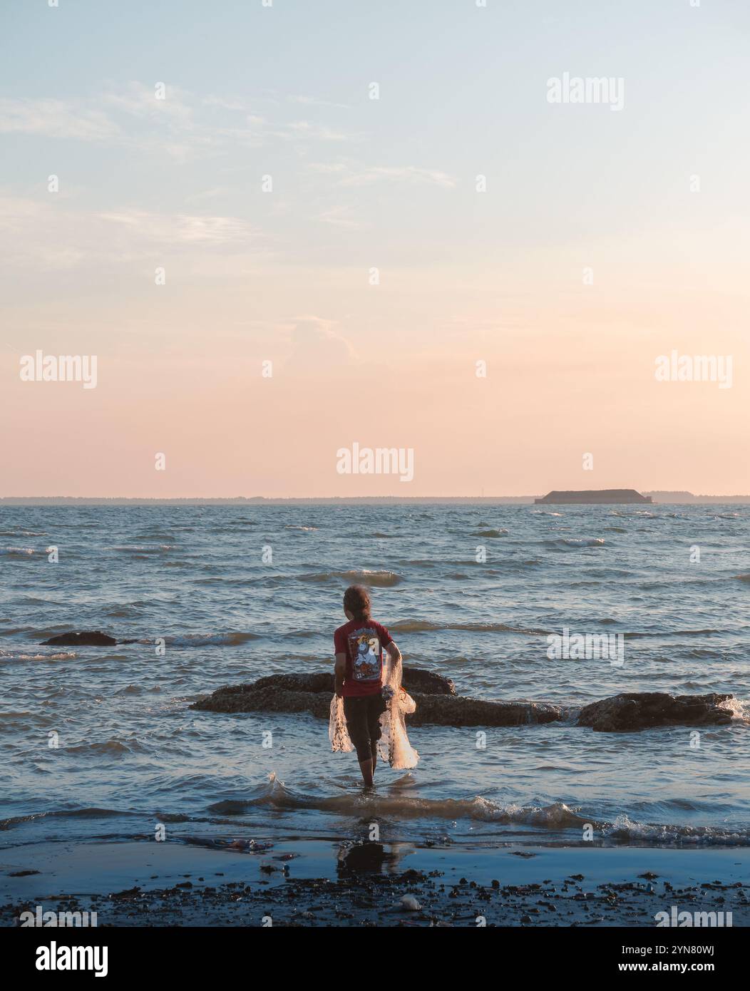 Un pescatore si prepara e aspetta il momento giusto per gettare la rete sulla spiaggia di Balikpapan, Kalimantan orientale, Indonesia Foto Stock