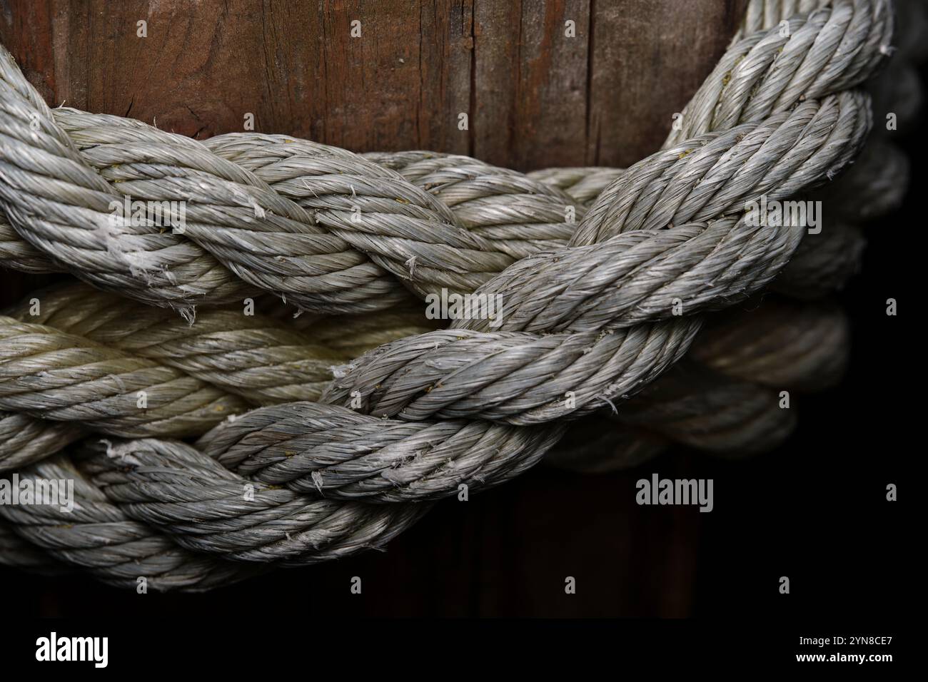 Primo piano della corda nautica intrecciata avvolta intorno a un palo di legno Foto Stock