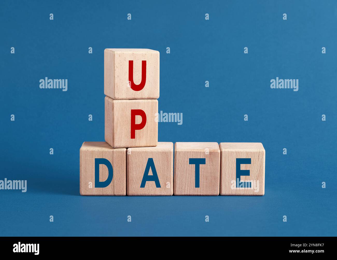 I cubi di legno si aggiornano su sfondo blu, simboleggiando il progresso nel business e nella tecnologia. Restate aggiornati e adattatevi per avere successo nell'era digitale Foto Stock