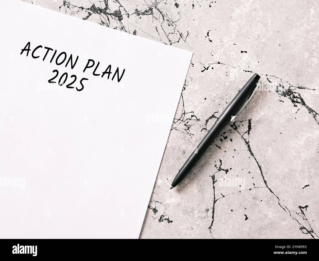 Piano d'azione aziendale per il 2025 scritto su foglio bianco con penna su scrivania in marmo, fissando obiettivi e obiettivi Foto Stock