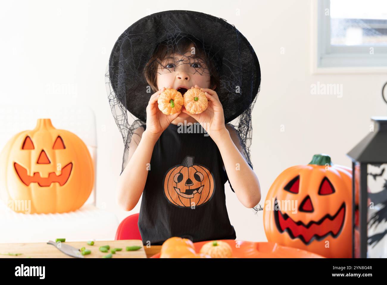 Ragazze che indossano costumi di Halloween e tengono in mano le zucche fatte di arance mandarine Foto Stock