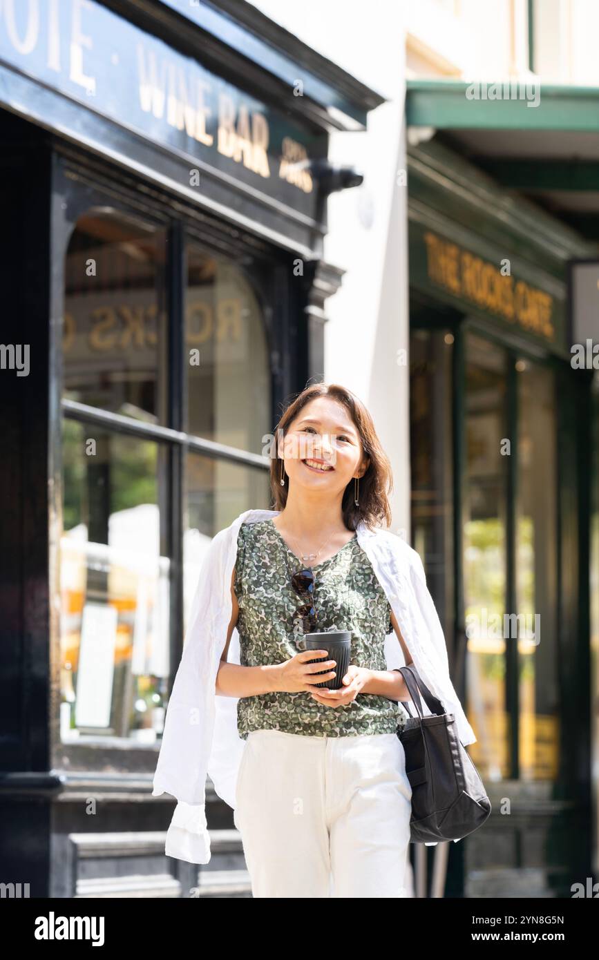 Donna che fa shopping con il caffè in mano Foto Stock