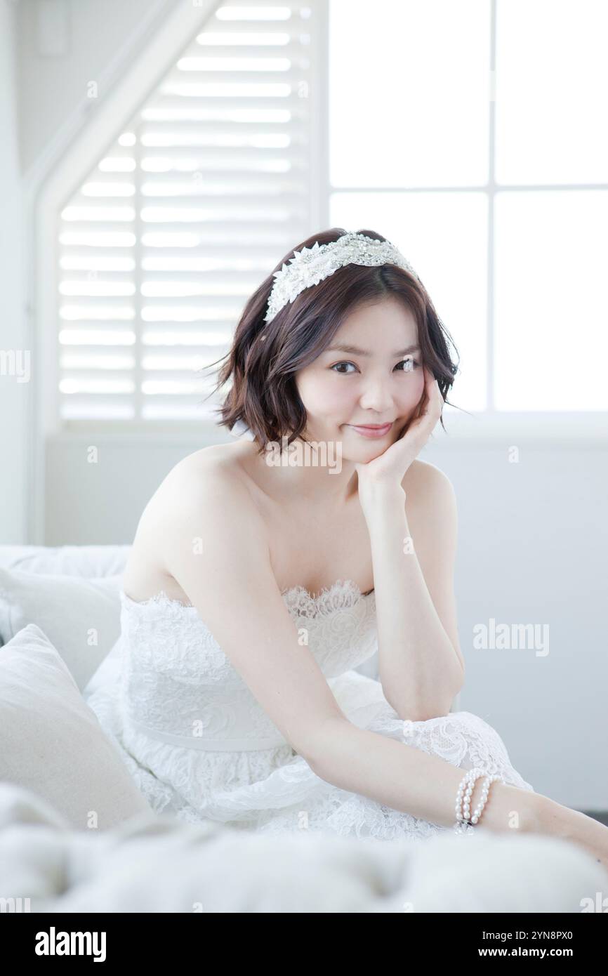 Donna in abito da sposa che riposa sui gomiti Foto Stock