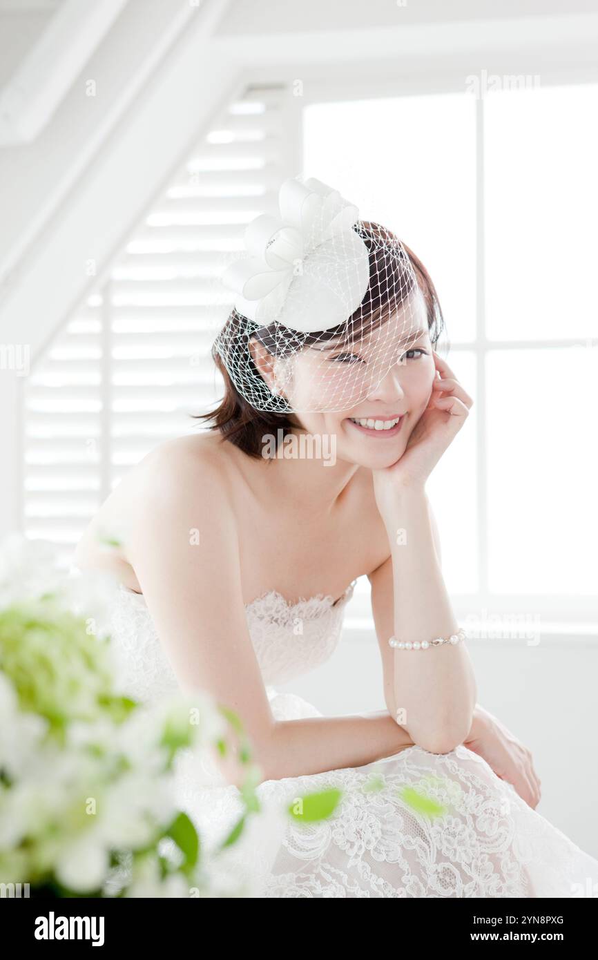 Donna in abito da sposa che riposa sui gomiti Foto Stock