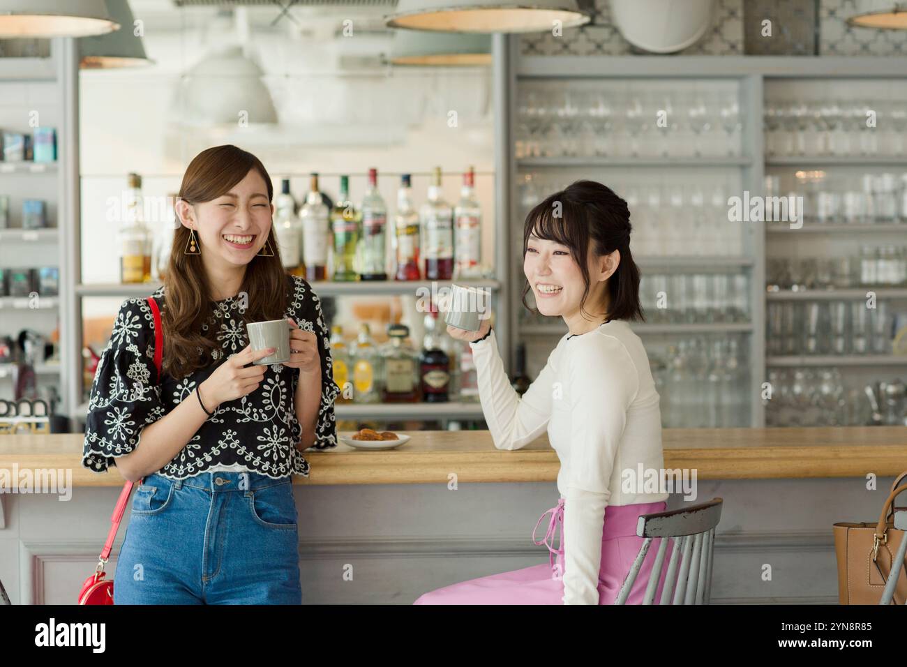 Due donne di 20 anni si godono il tè in un caffè mentre le donne di 20 anni si godono il tè in un bar Foto Stock
