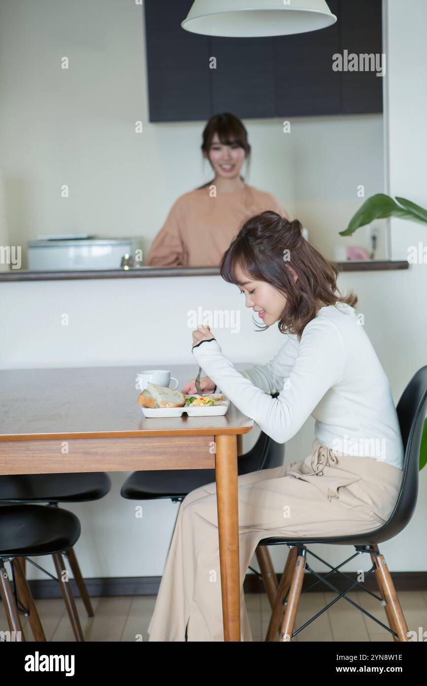 Donna sui vent'anni che mangia nella sua stanza Foto Stock