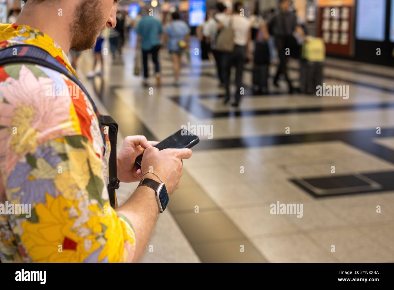 Pendolari che utilizzano lo smartphone in una stazione ferroviaria urbana molto trafficata Foto Stock