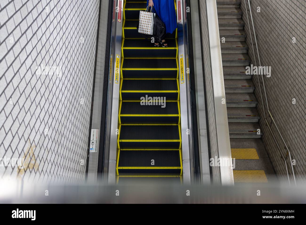 Persona su scala mobile alla stazione della metropolitana Foto Stock