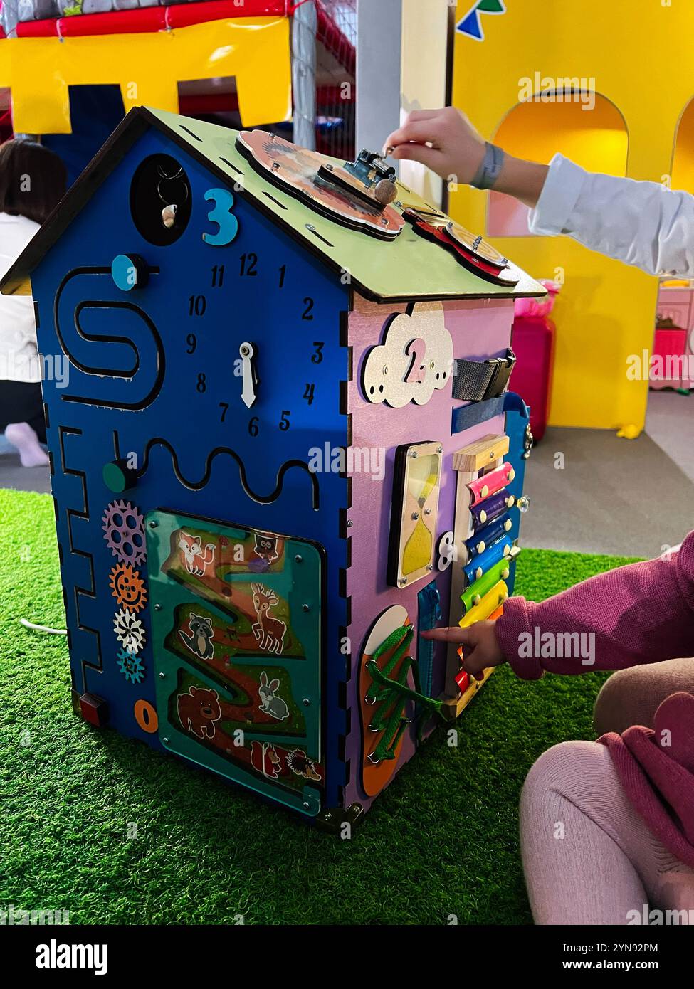 Pannello di gioco interattivo colorato progettato per l'apprendimento e l'esplorazione dei bambini. Offre varie attività coinvolgenti come orologio, ingranaggi e animali. Foto Stock